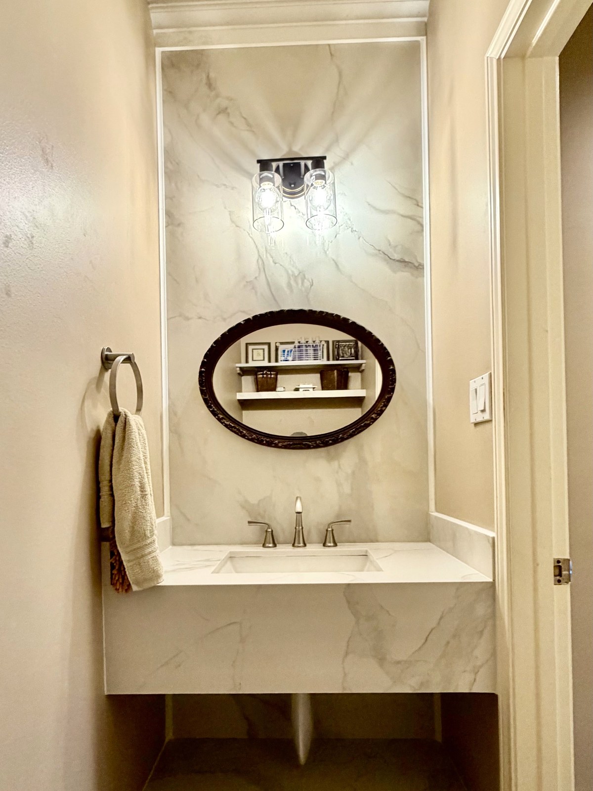 Powder room by Haven Renovations — book-matched marble-look surround with a floating stone vanity