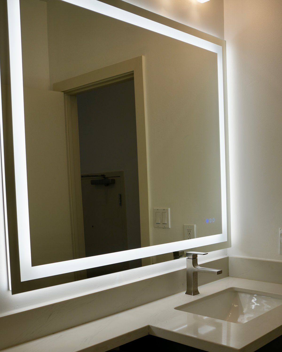 Powder room by Haven Renovations — floating dark vanity with quartz top and lit mirror