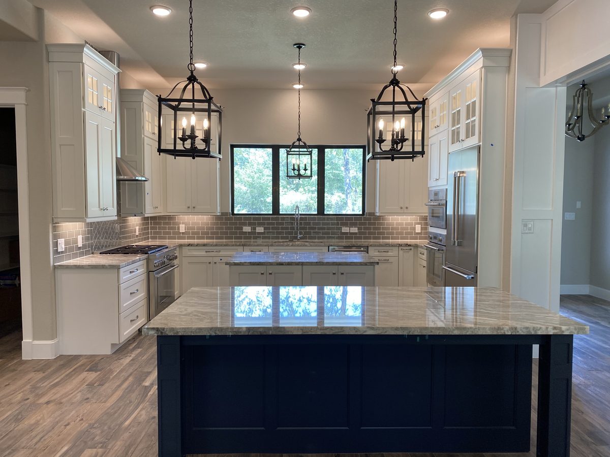 Custom kitchen by Haven Renovations — lantern pendants, stone top