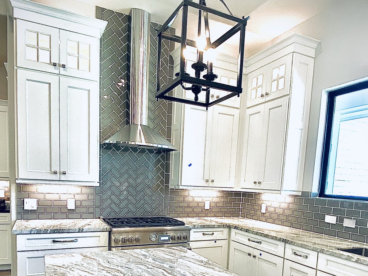 Custom kitchen by Haven Renovations — chandelier, painted cabinetry