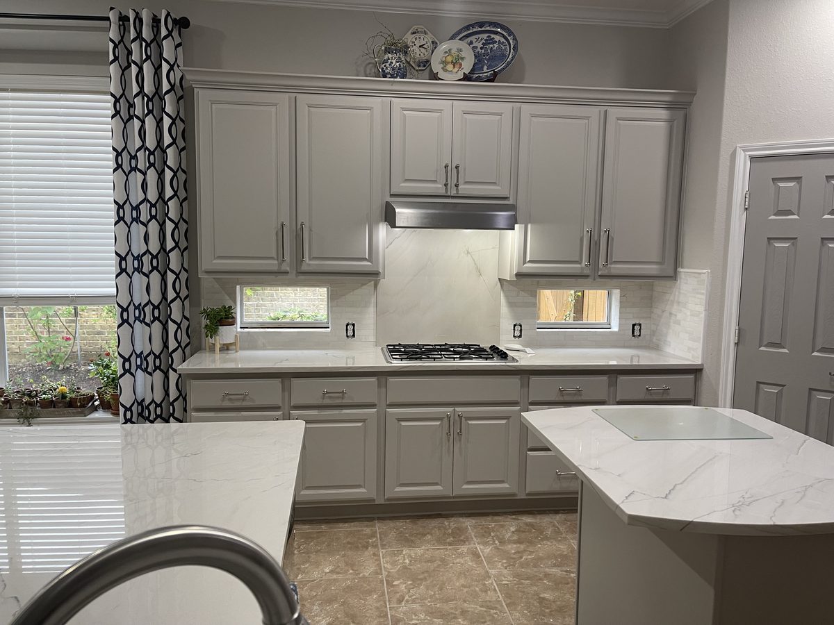 Custom kitchen by Haven Renovations — veined stone, vent hood
