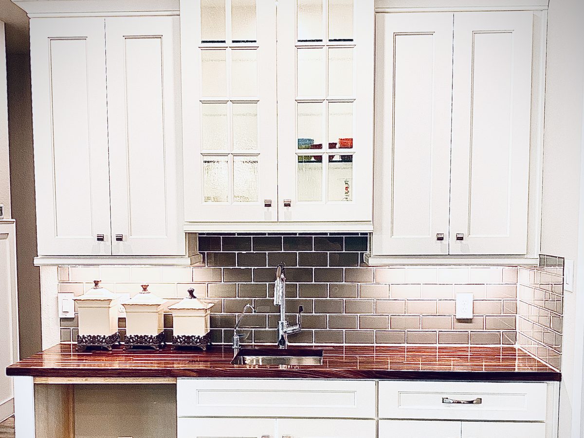 Custom kitchen by Haven Renovations — white cabinetry, brick surround