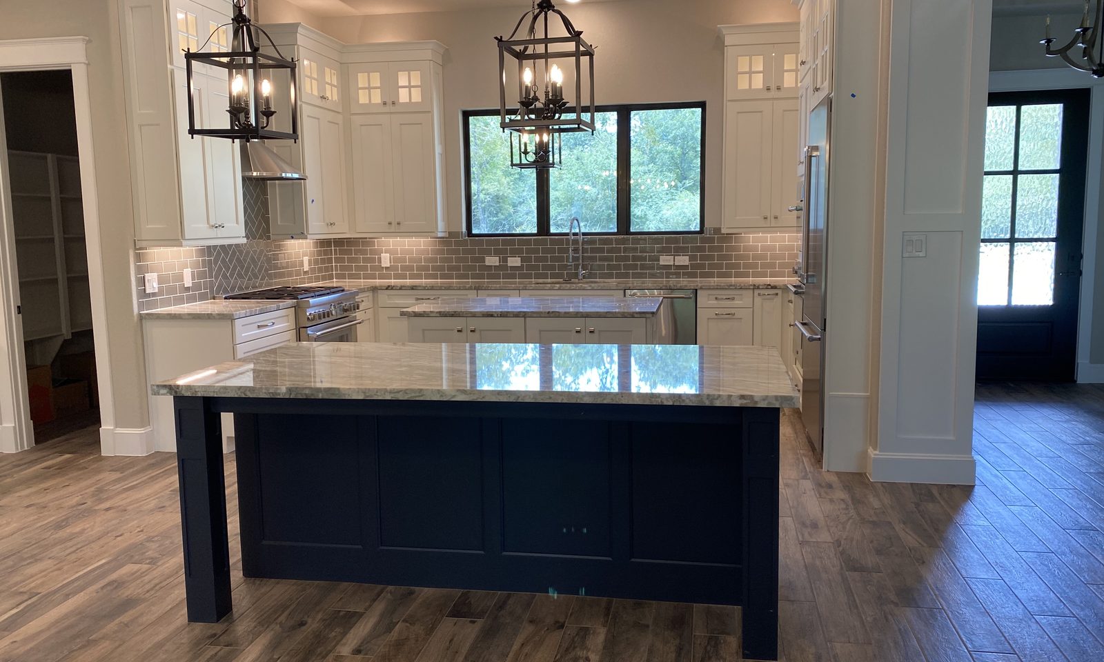 Custom kitchen by Haven Renovations — navy island with lantern pendants