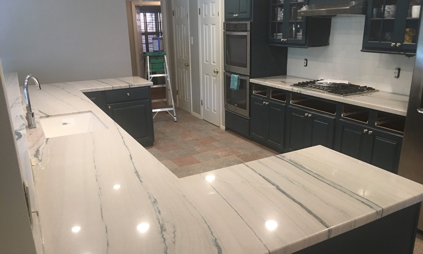 Custom kitchen by Haven Renovations — deep green cabinetry with waterfall counters