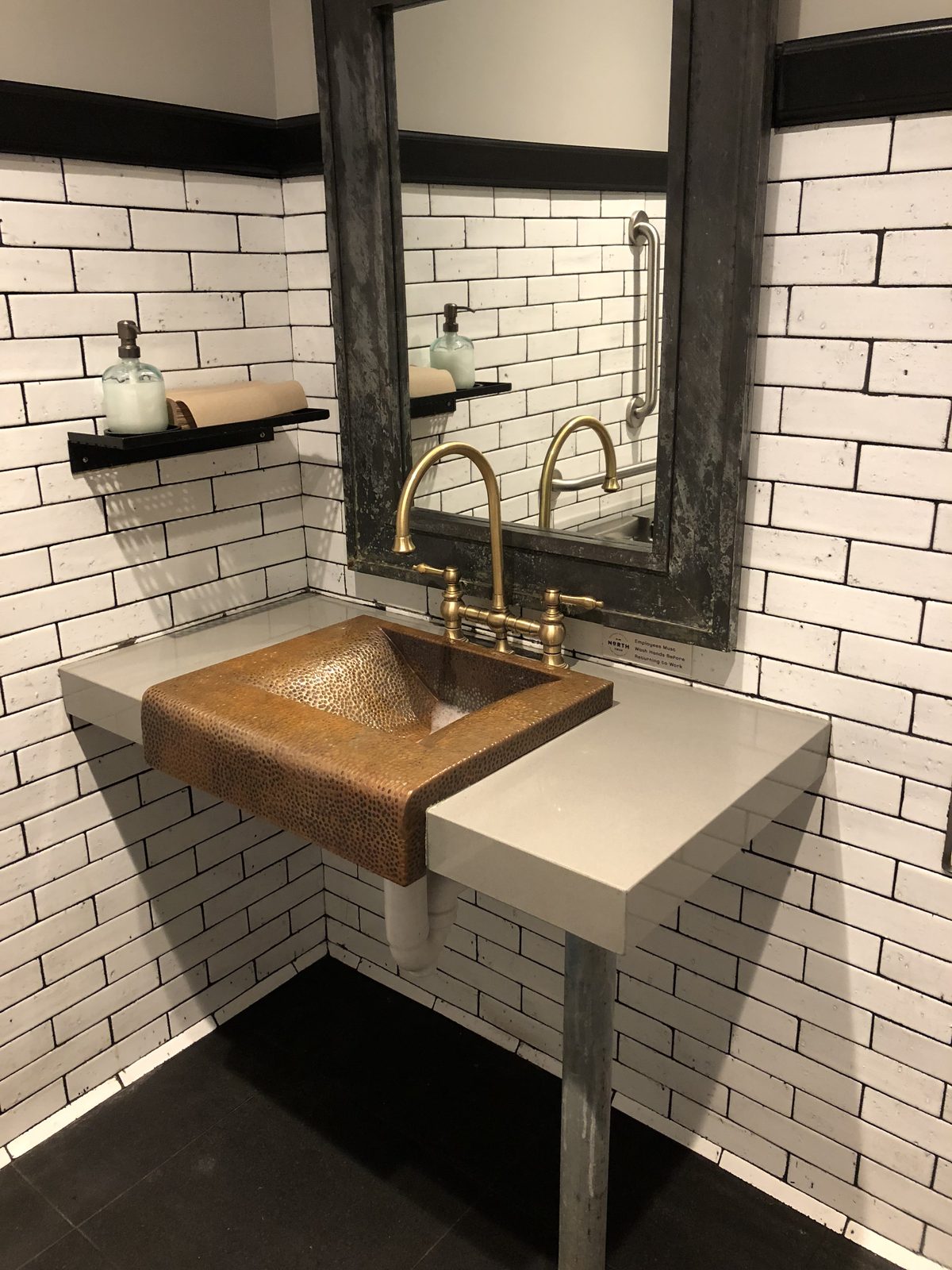 Hammered copper vessel sink on a floating console with subway tile