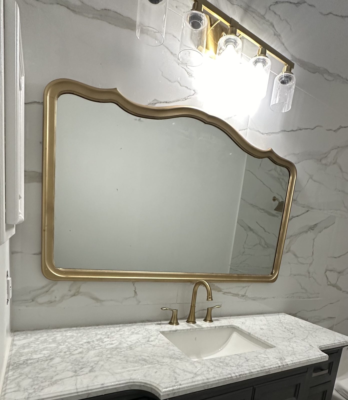 Ornate brass mirror above a marble-top vanity