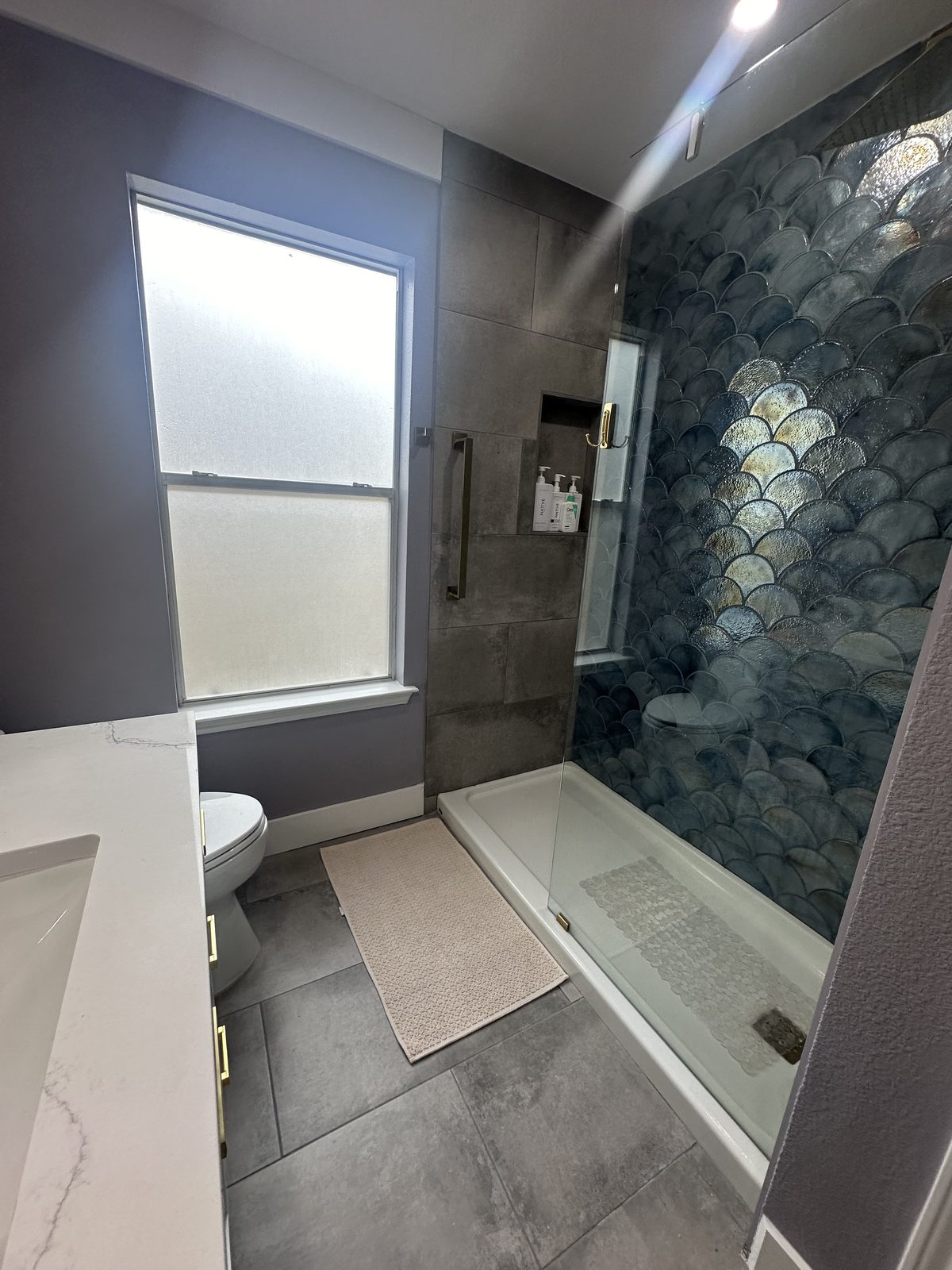 Blue scale-tile shower with frameless glass