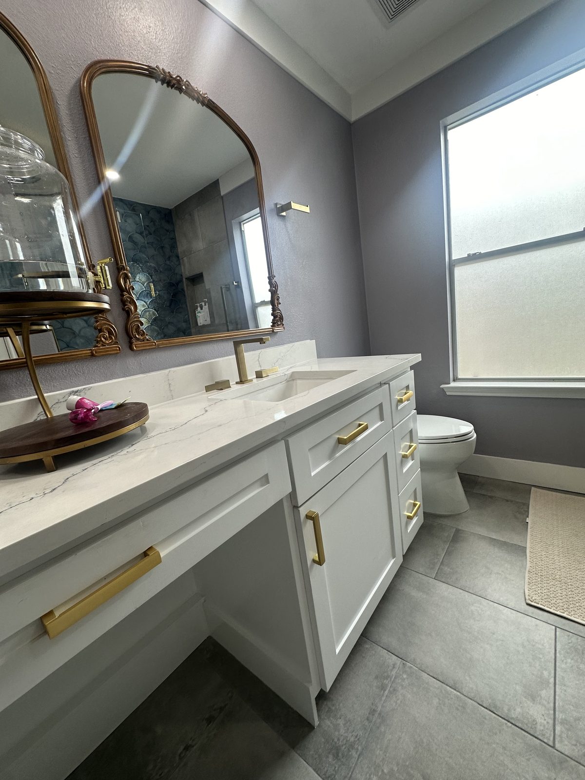 Gold fixture double vanity with gray tile floor