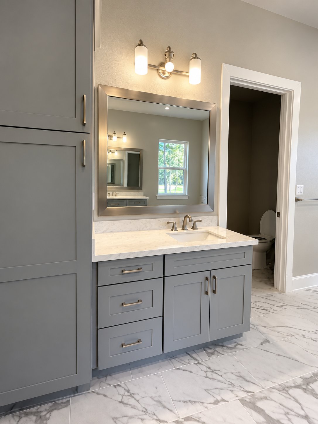 Gray Shaker vanity with marble floor and an ensuite water closet