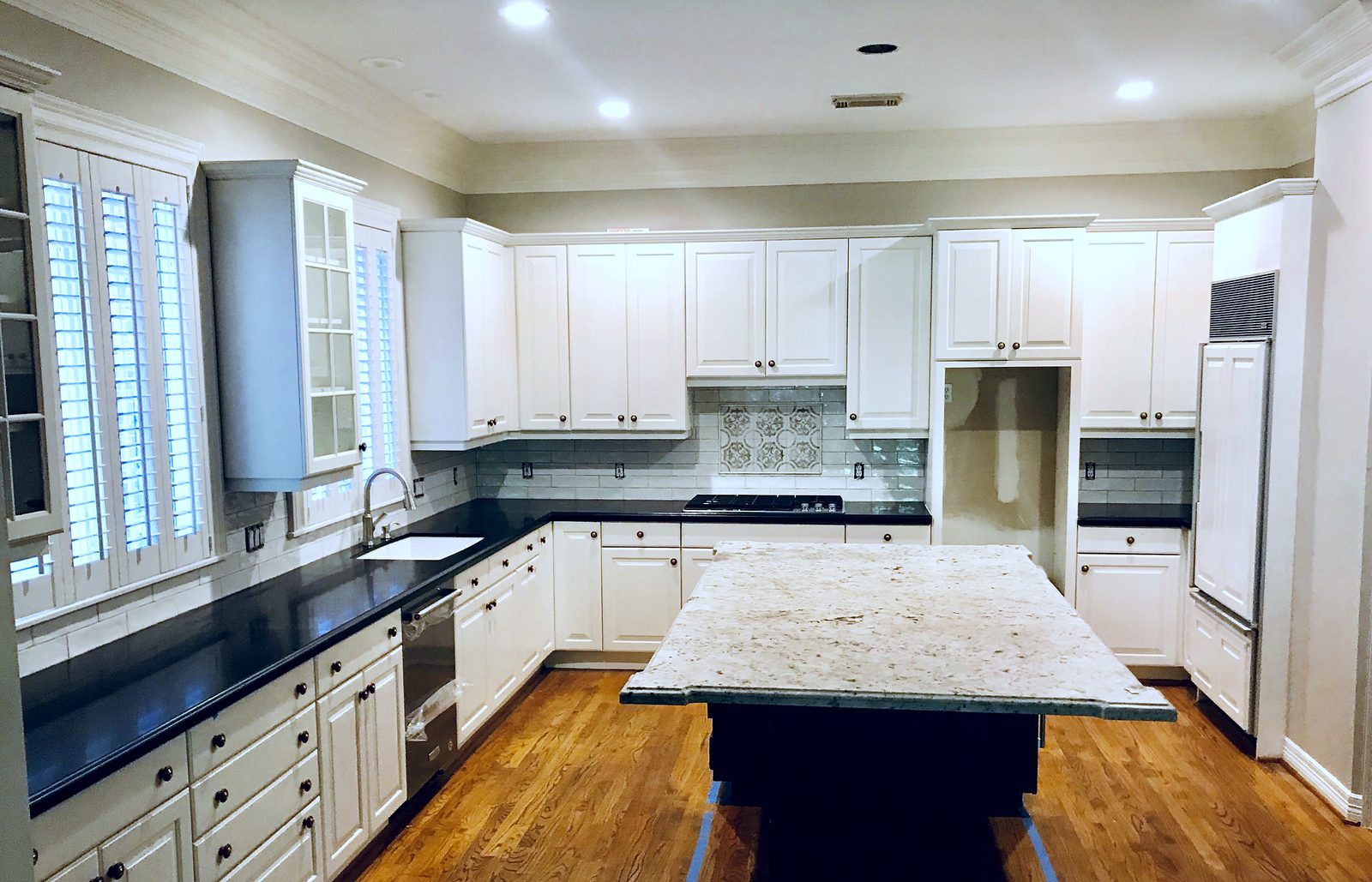 Custom kitchen by Haven Renovations — black counters, hardwood floors