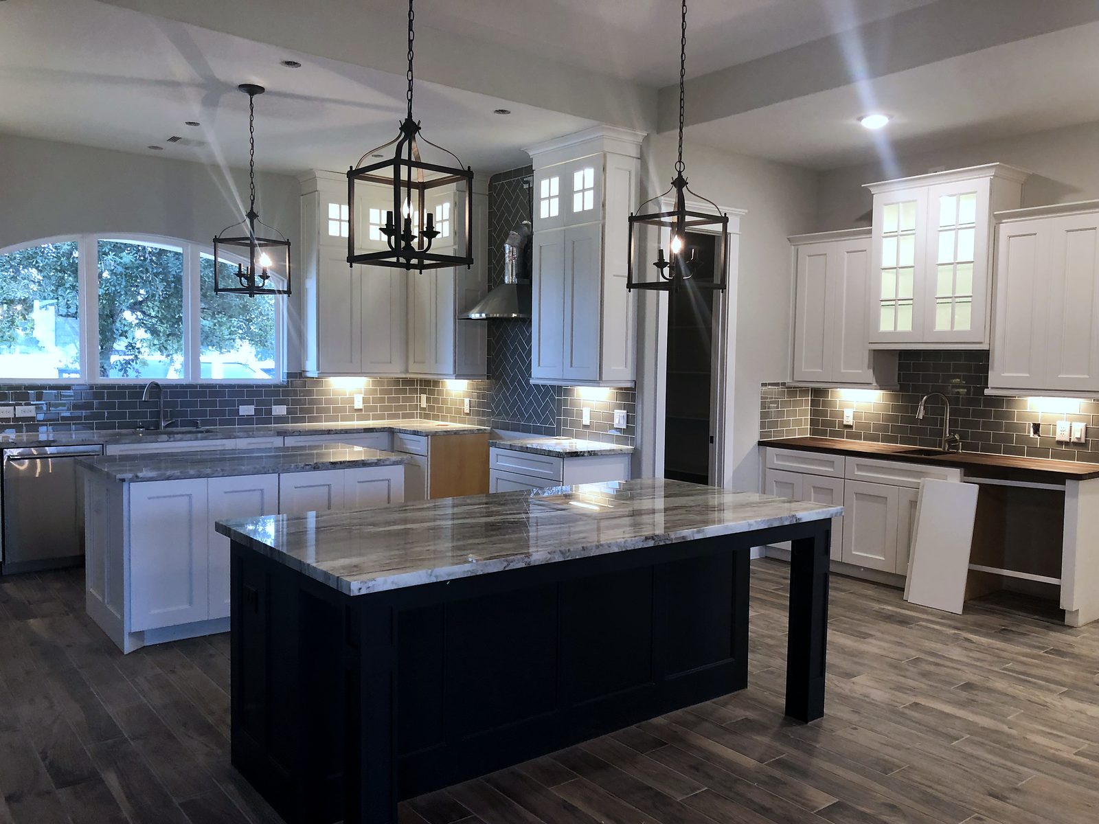 Custom kitchen by Haven Renovations — lantern pendants, subway tile
