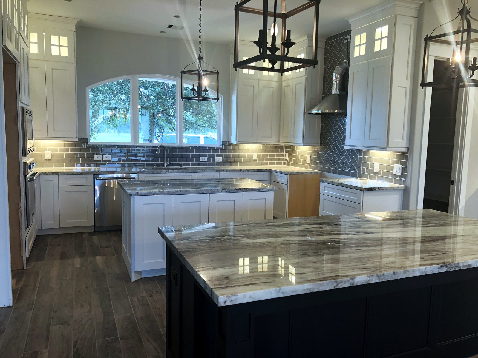 Custom kitchen by Haven Renovations — lantern pendants, plank floors