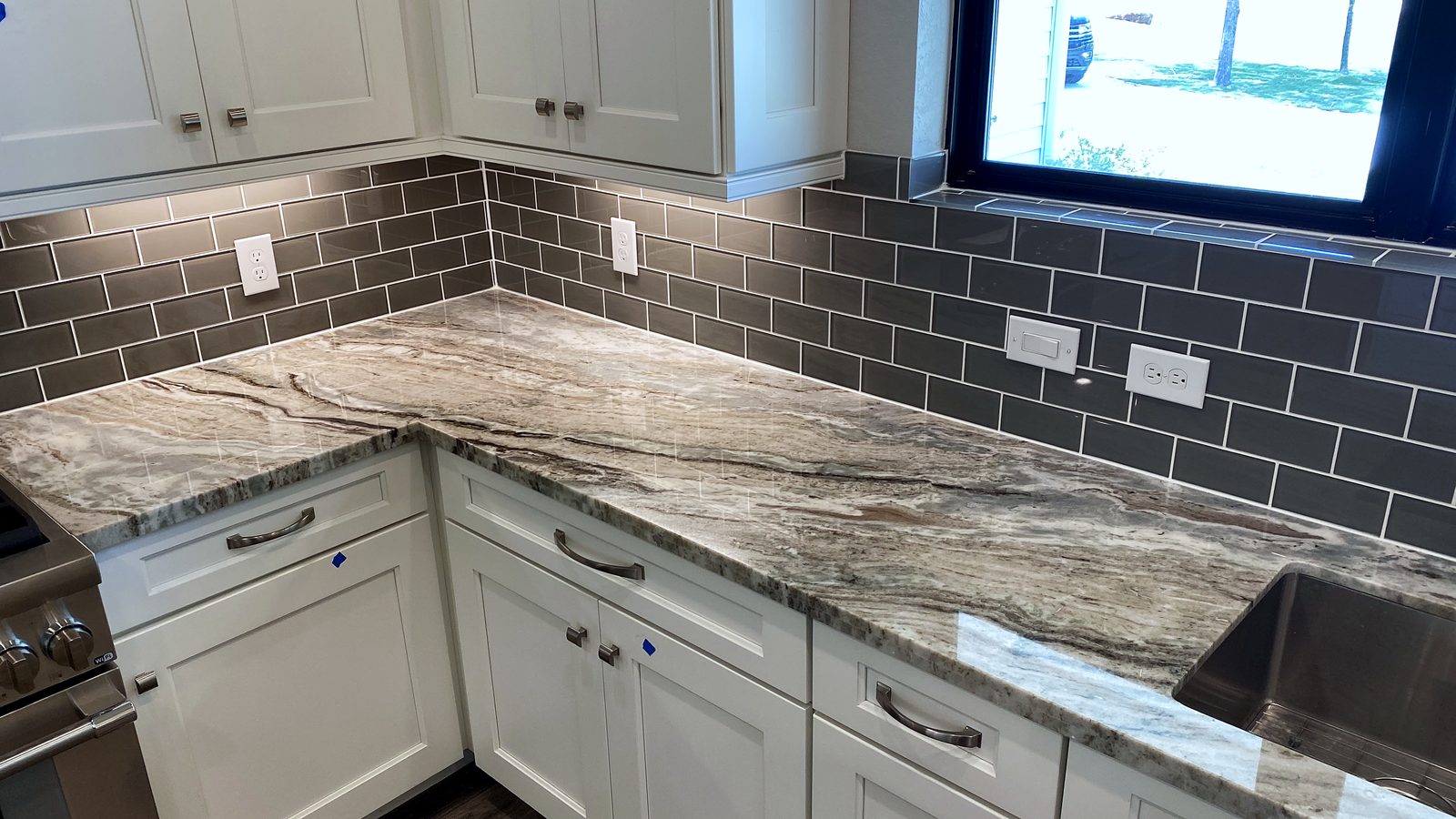 Custom kitchen by Haven Renovations — veined stone, white cabinetry